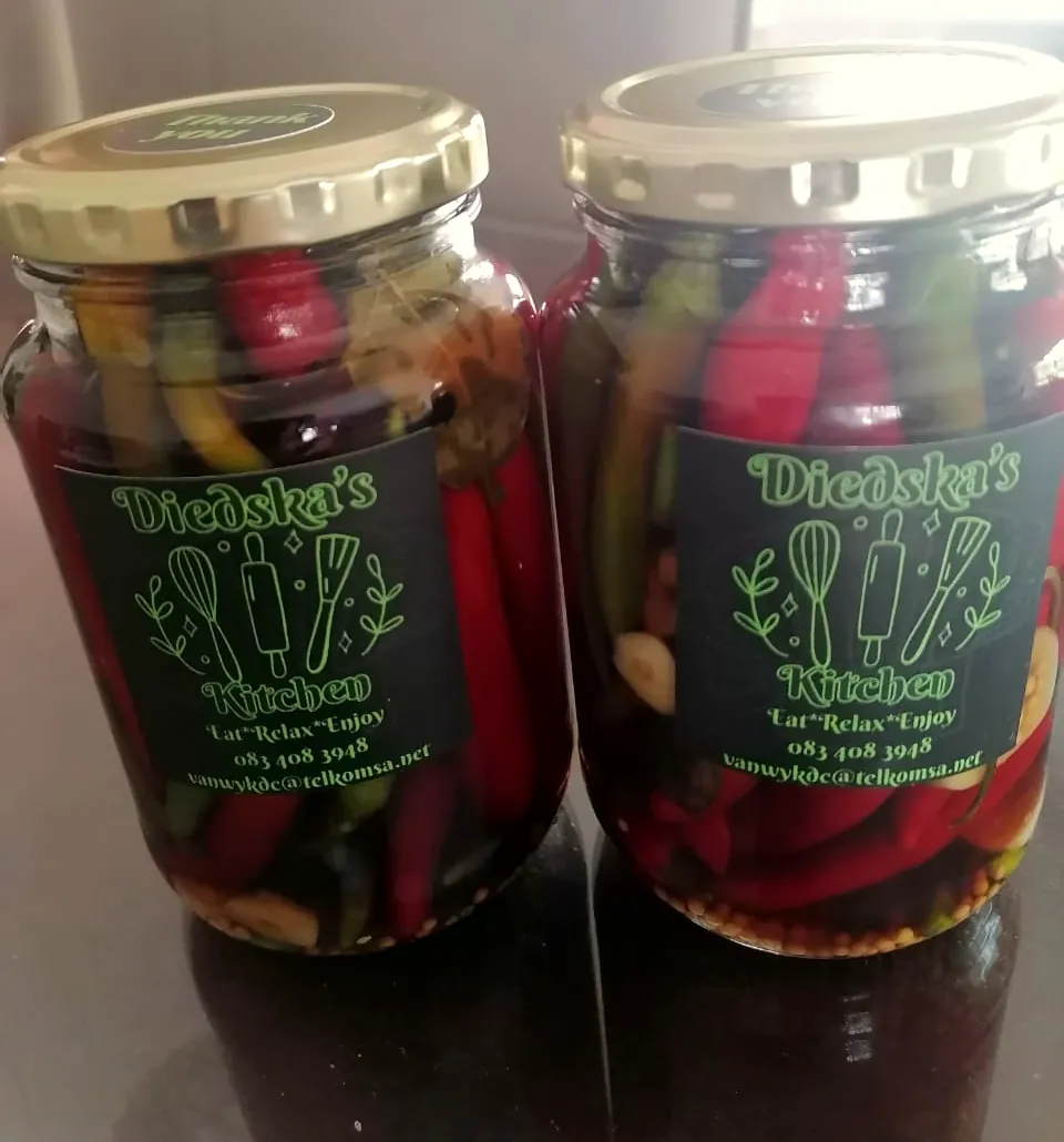 Two jars of whole pickled red and green chillies with garlic